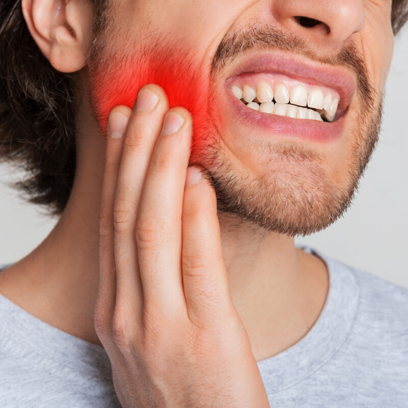 man touching jaw or cheek with red spot highlighting deep pain
