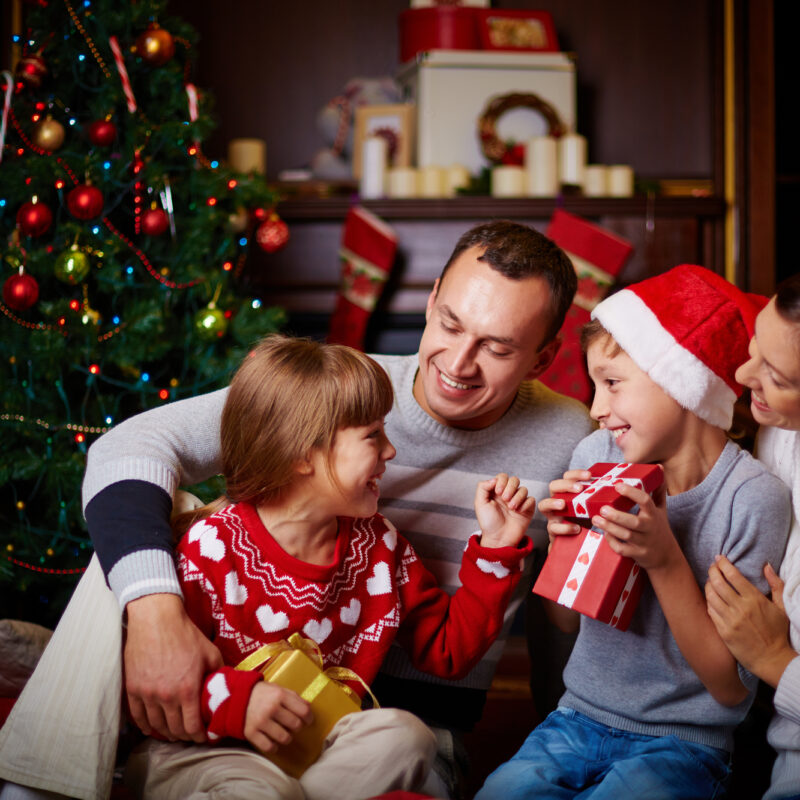 family of four sitting on couch opening Christmas presents