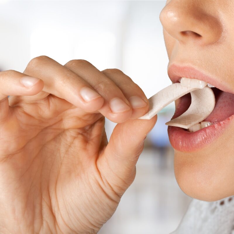 woman putting gum in her mouth to cover up bad breath