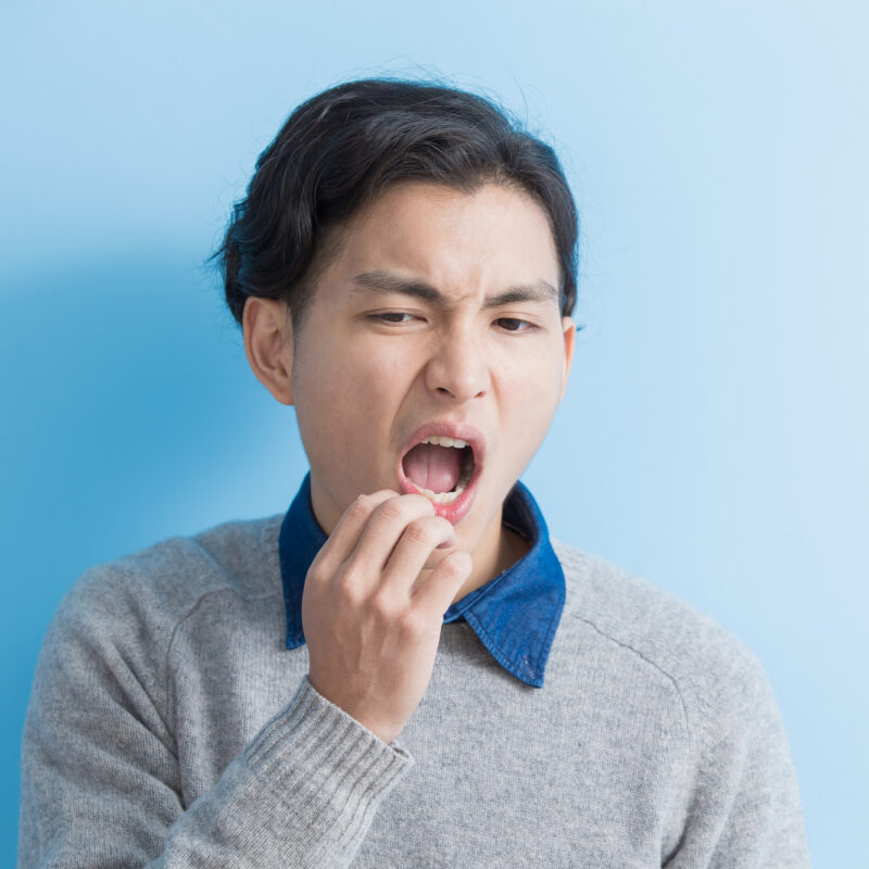 young man with a toothache on blue background