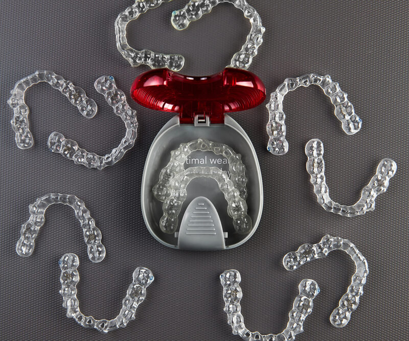 clear aligners in case and surrounded by other clear aligners on table
