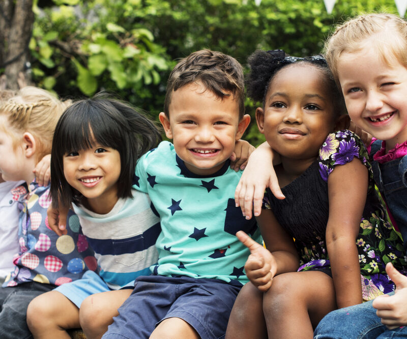 Group of kindergarten kids friends arm around sitting and smiling fun