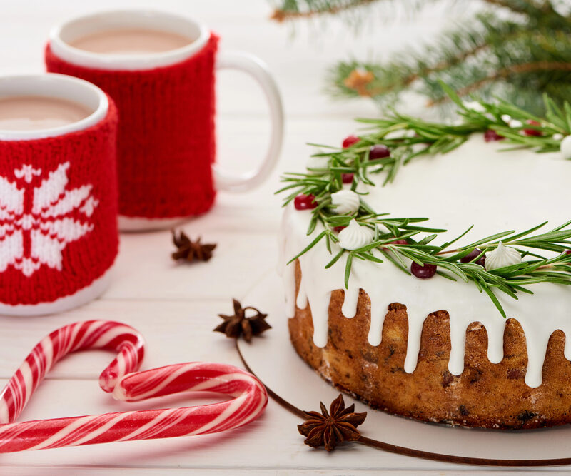 holiday cake, candy canes, and two mugs of hot chocolate sitting on a festive table