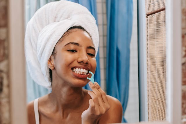 young beautiful black woman flossing her teeth with a towel on her head