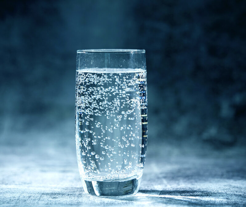 glass of sparkling water on blue background