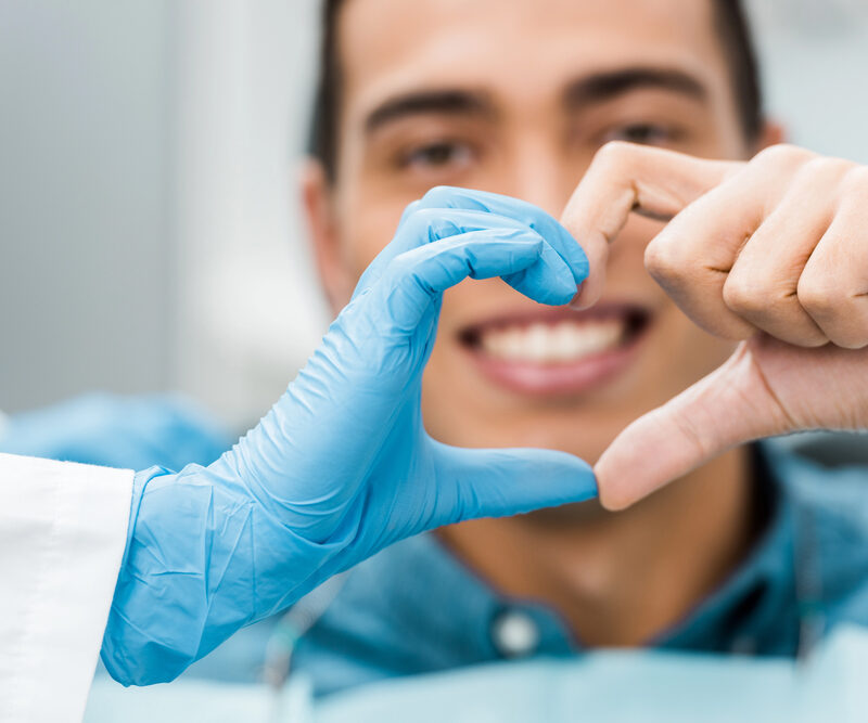 dentist and patient making a heart shape by putting their fingers together