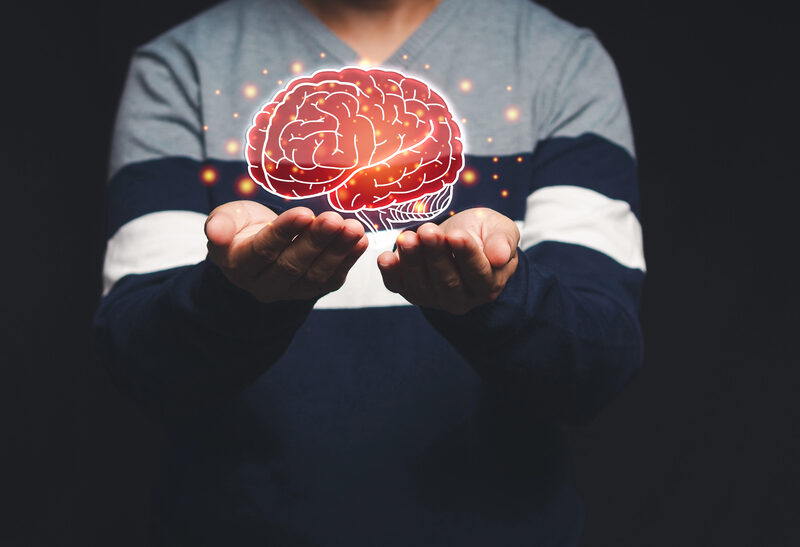 man holding depiction of brain in the palm of his hands