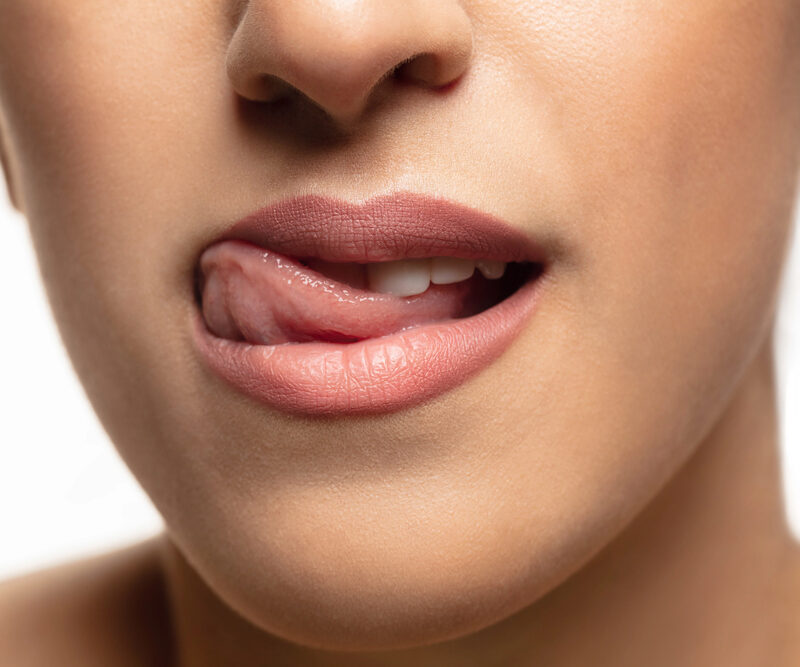 close up of woman rubbing her tongue along her top teeth