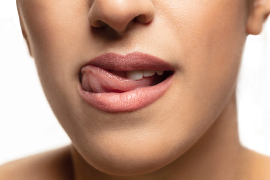 close up of woman rubbing her tongue along her top teeth