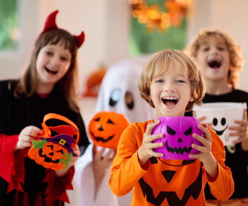 happy kids holding their halloween candy and wearing costumes