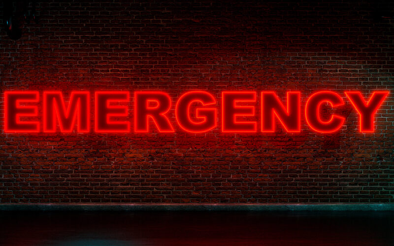 "EMERGENCY" in neon red letters on brick wall