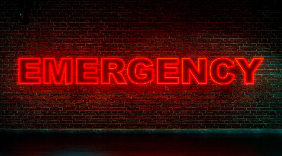 "EMERGENCY" in neon red letters on brick wall