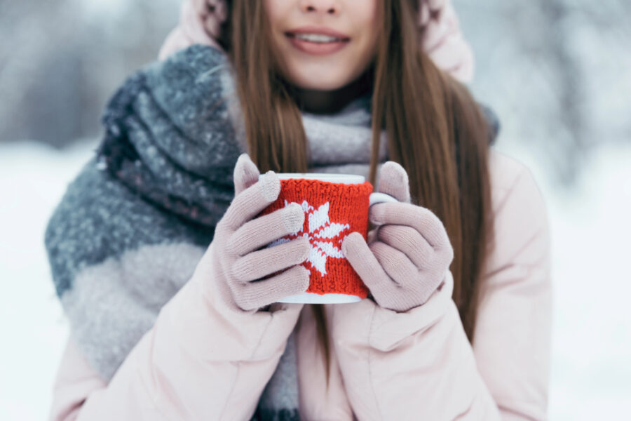 woman with cup of hot coffee in hands in snowy park