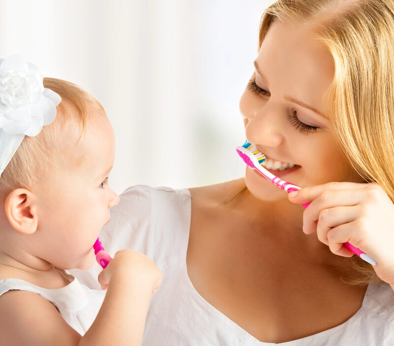 mother teaching daughter how to brush her teeth