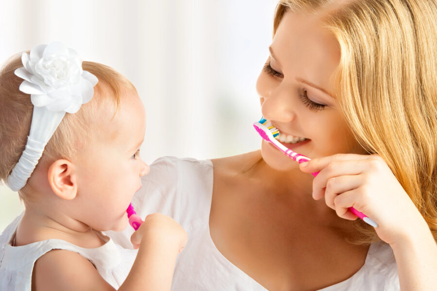 mother teaching daughter how to brush her teeth